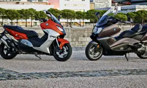 Dwa skutery BMW C650GT: jeden pomarańczowo-srebrny, drugi brązowy, stojące na kamiennym placu.