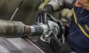 Mechanik w rękawiczkach montuje przegub wału kardana.
