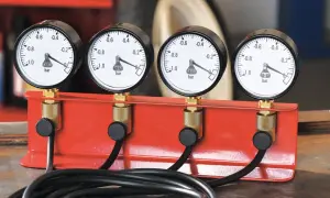 Zestaw czterech manometrów do synchronizacji gaźników, zamontowany na czerwonej podstawie.