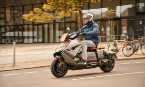 Mężczyzna w kasku jedzie na futurystycznym skuterze BMW CE04 po mieście.