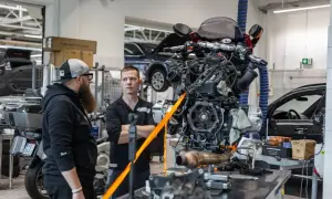 Mechanicy omawiają regulację linki sprzęgła przy silniku motocykla wiszącym na taśmach.