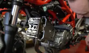 Mechanik pracuje nad silnikiem motocykla, pokazując, jak ustawić zawory.