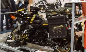 Czarny motocykl BMW R1250 GS z żółtymi akcentami, przygotowany do transportu motocykla w busie. Na kufrach mapy świata i naklejki.