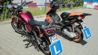 Dwa pojazdy z literą "L" na tablicy, gotowe do nauki jazdy. Czerwony motorower i pomarańczowy skuter.