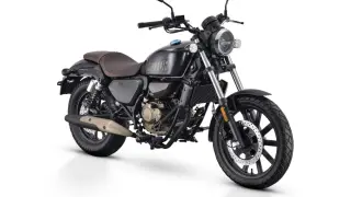 Czarny motocykl w stylu retro, z brązowym siedzeniem i złotymi elementami silnika. To najmocniejsze 125 na b, gotowe na każdą drogę.
