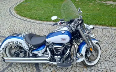 Błękitno-biały Yamaha Road Star 1700 lśni chromem na brukowanym podjeździe, gotowy na przygodę.