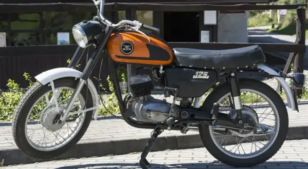 Pomarańczowy motocykl WSK 125 modele, klasyk z lat 70., gotowy do podróży.