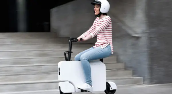 Uśmiechnięta kobieta w kasku jedzie na białym Honda Motocompacto, pokonując miejskie schody.