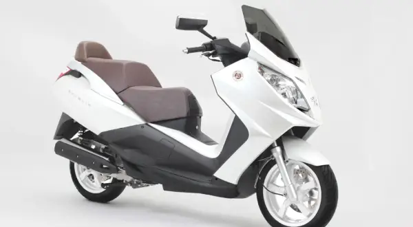 Biały skuter Peugeot Satelis z brązową kanapą, gotowy na miejskie podróże.