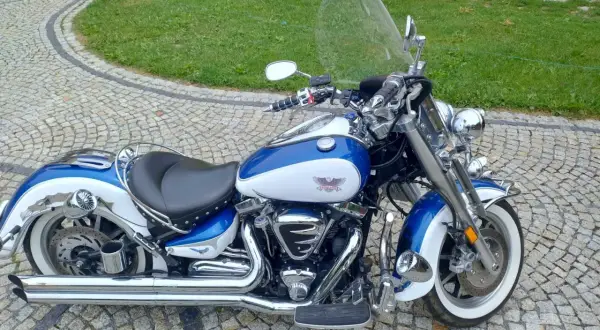 Błękitno-biały Yamaha Road Star 1700 lśni chromem na brukowanym podjeździe, gotowy na przygodę.
