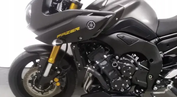 Czarny motocykl Yamaha FZ8N z żółtym napisem "FAZER" na owiewce. Złote lagi i detale podkreślają sportowy charakter.
