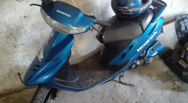 Niebieski skuter Honda Dio z niebieskim kaskiem ozdobionym płomieniami.