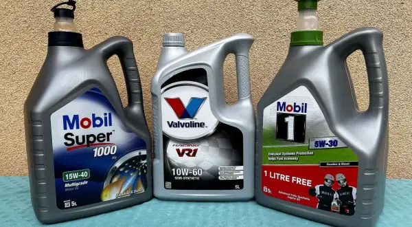 Trzy bańki z olejem silnikowym: Mobil Super 1000, Valvoline VR1 i Mobil 1. Wybór między olejem syntetycznym czy mineralnym zależy od potrzeb silnika.