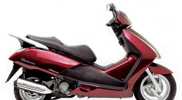 Elegancki, czerwony skuter Honda Pantheon z czarnym siedzeniem i chromowanym bagażnikiem, gotowy na miejskie przygody.