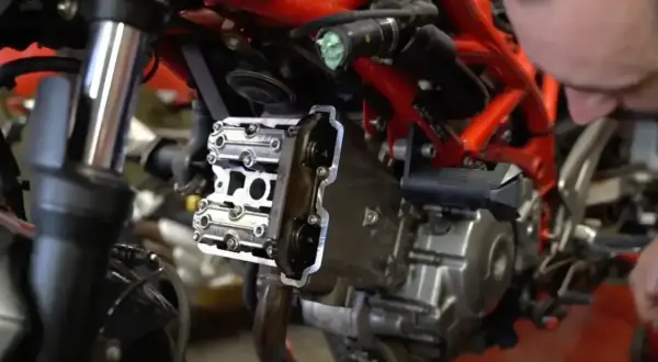 Mechanik pracuje nad silnikiem motocykla, pokazując, jak ustawić zawory.