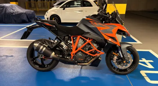 Pomarańczowo-szary KTM 1290 Super Duke w garażu, obok białego Fiata 500.