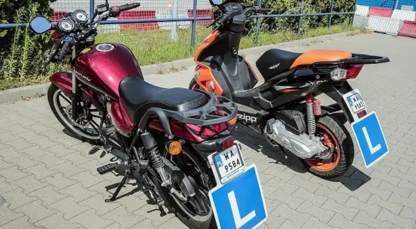 Dwa motocykle, jeden czerwony, drugi pomarańczowy, z literą "L" na tablicach. Idealne do nauki jazdy na kat. AM.
