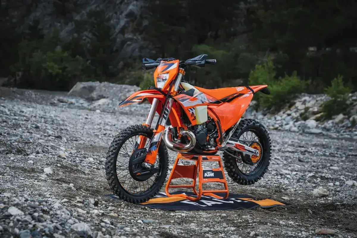Pomarańczowy KTM EXC 300 2T na stojaku, gotowy do jazdy w terenie. Sprawdź jego dane techniczne!