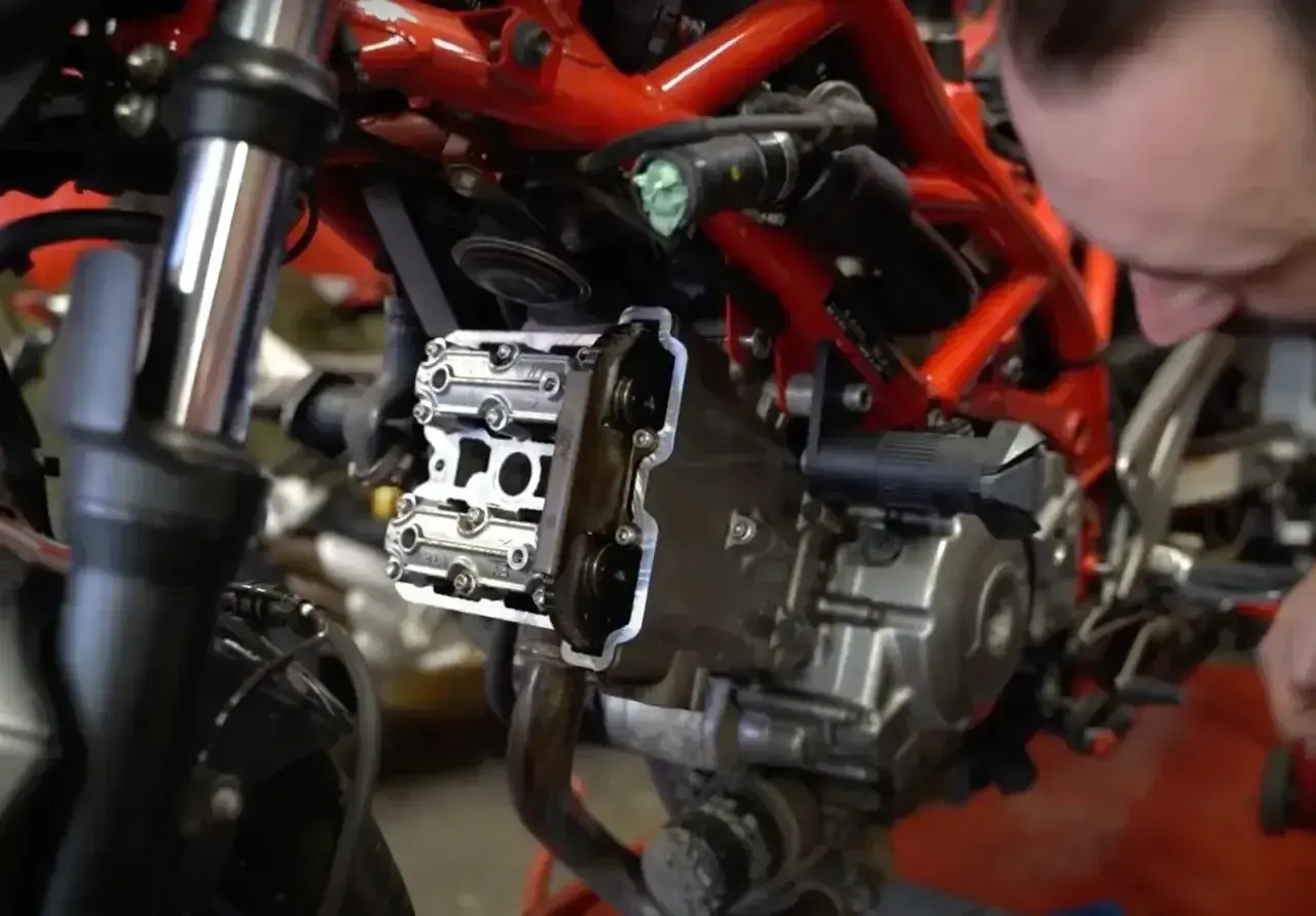 Mechanik pracuje nad silnikiem motocykla, pokazując, jak ustawić zawory.