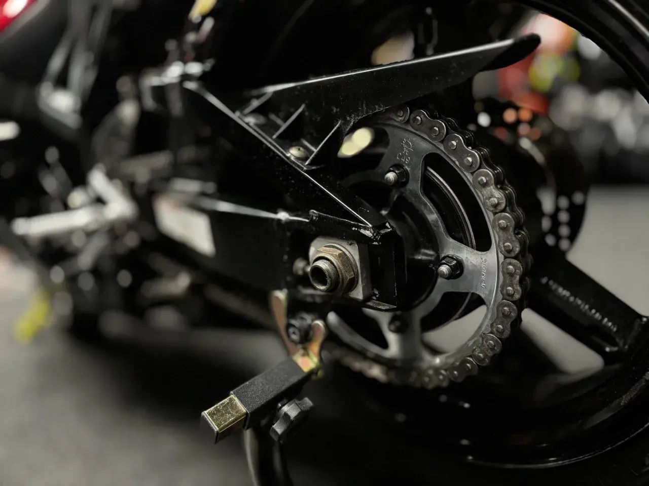 Zbliżenie na zębatkę i łańcuch motocyklowy. Dowiedz się, czym czyścić łańcuch motocyklowy, by był jak nowy.