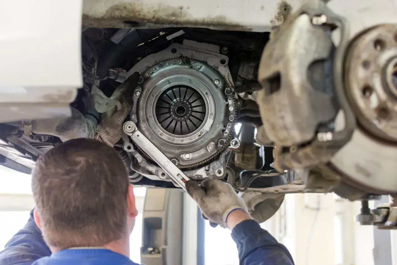 Mechanik dokonuje wymiany sprzęgła w samochodzie, używając klucza dynamometrycznego do precyzyjnego dokręcenia śrub.