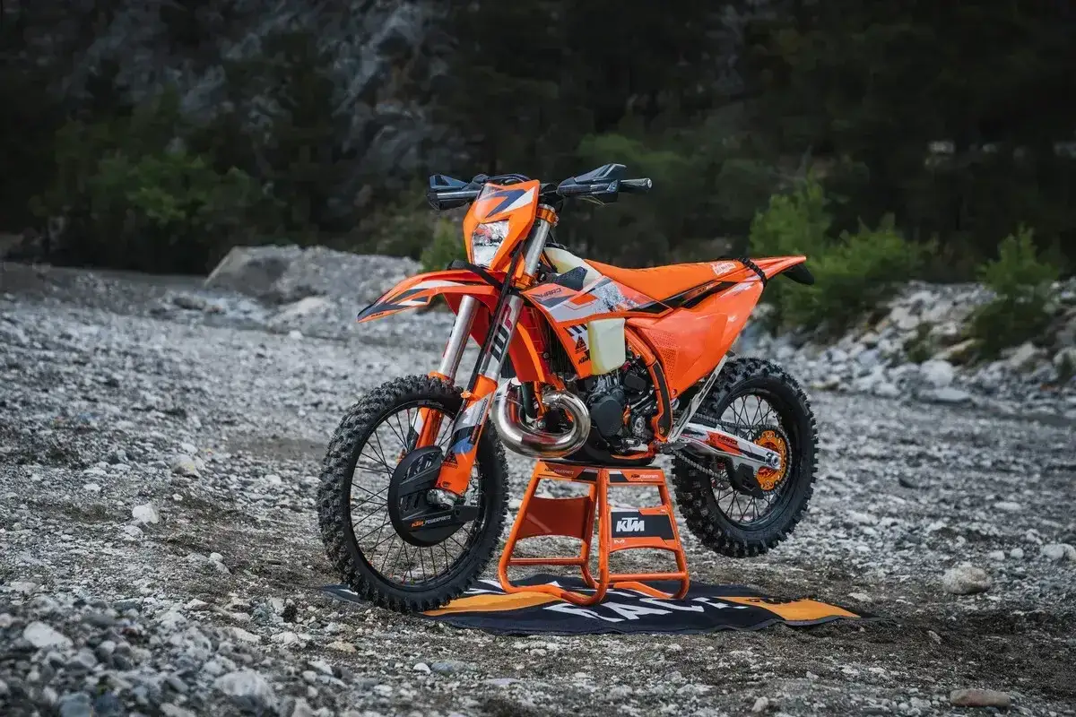Pomarańczowy KTM EXC 300 2T na stojaku, gotowy do jazdy w terenie. Poznaj jego dane techniczne!