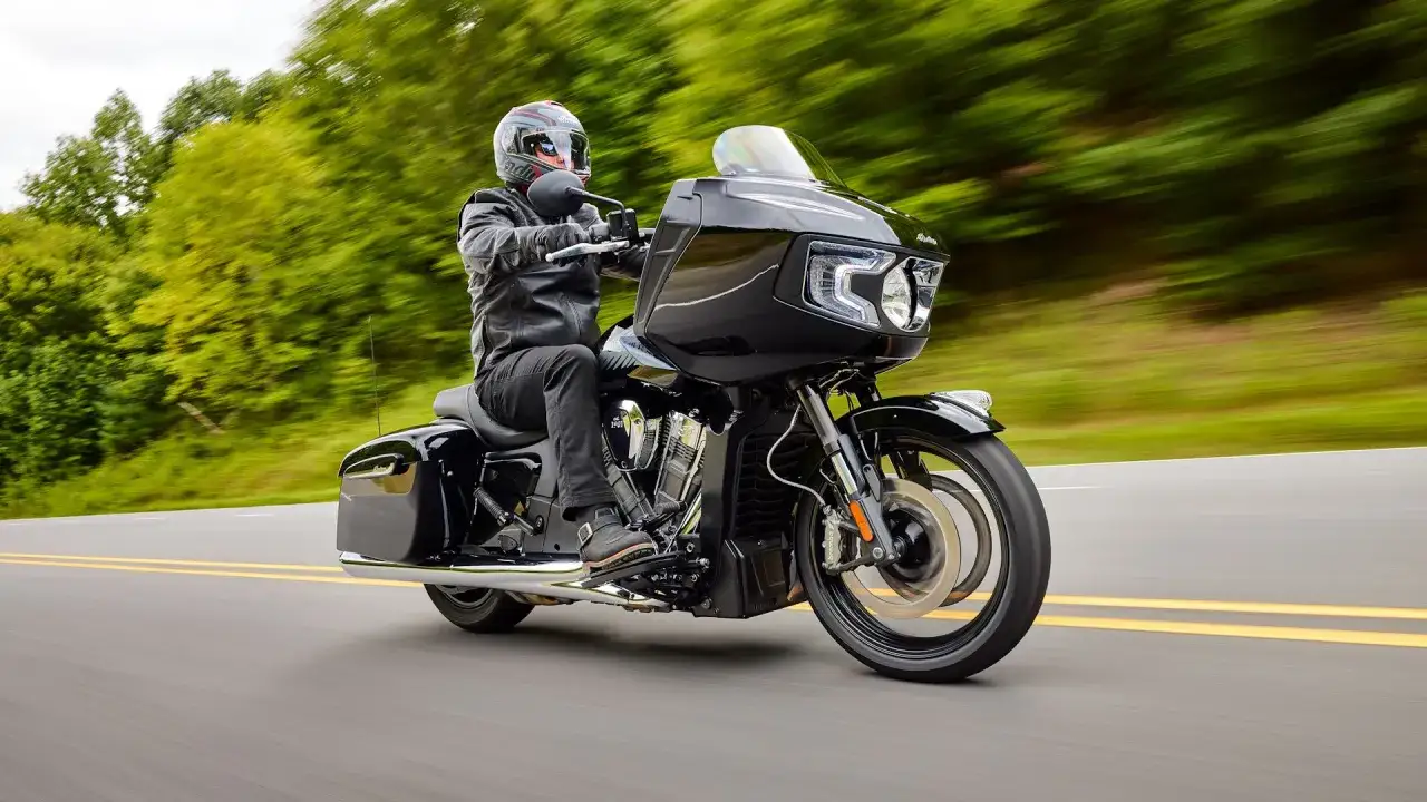 Czarny, potężny motocykl z USA mknie po drodze, otoczony zielenią.