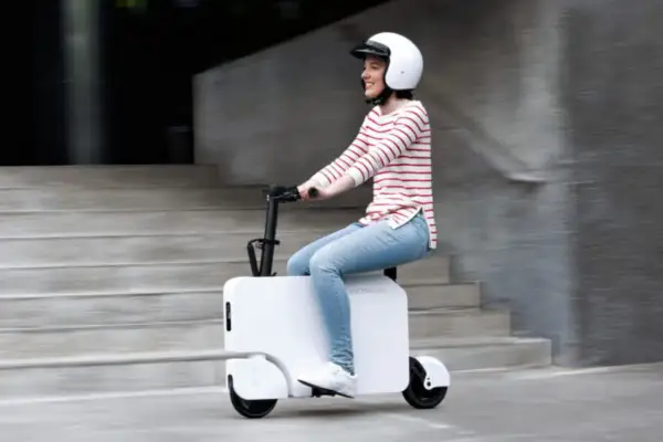 Uśmiechnięta kobieta w kasku jedzie na białym Honda Motocompacto, pokonując miejskie schody.