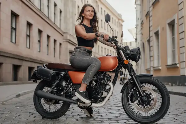 Dziewczyna na motocyklu 125, gotowa na jazdę po mieście. Stylowa, pewna siebie, z uśmiechem na twarzy.