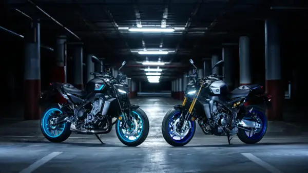 Dwa motocykle Yamaha MT, w tym jeden z niebieskimi felgami, prezentują swoją hyper naked estetykę w mrocznym garażu.