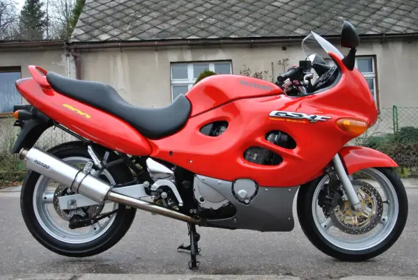 Czerwony motocykl Suzuki GSX-F 600 z czarnym siedzeniem, zaparkowany przed budynkiem.