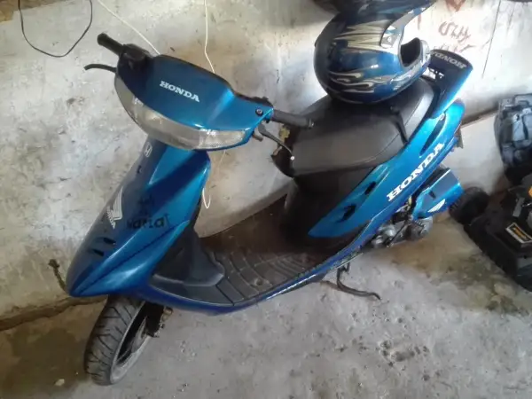 Niebieski skuter Honda Dio z niebieskim kaskiem ozdobionym płomieniami.