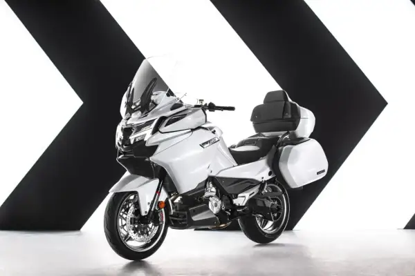 Biały, turystyczny motocykl z kuframi, jeden z nowoczesnych chińskich motocykli, prezentowany na tle czarno-białej grafiki.