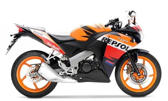 Pomarańczowy motocykl Honda CBR 125R w barwach Repsol, gotowy do wyścigów.